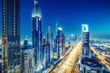 Fototapeta Miasto - Colorful skyline of a big modern city with illuminated skyscrapers and highways. Aerial view over downtown Dubai, UAE. Travel and architectural background.