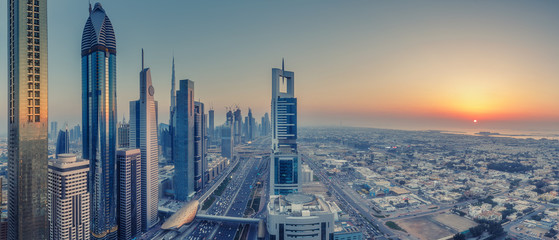 Skyscrapers and highways of a big modern city at sunset. Aerial panoramic view on downtown Dubai, United Arab Emirates.