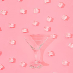 Wall Mural - Ice cubes pattern with martini glass on pastel pink background. Minimal summer drink concept. Flat lay.