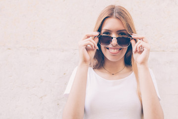 Wall Mural - Joyful pretty lady putting sunglasses on and looking at camera. Cheerful attractive girl having personal style. Lifestyle concept