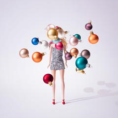Wall Mural - girl doll in silver glittering dress with colorful christmas baubles decoration. creative minimal fa