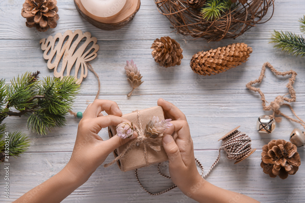 Child wrapping Christmas gift at wooden table, top view