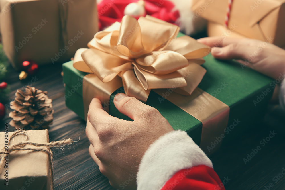 Santa Claus holding gift box on wooden table