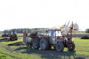 Tractors and excavator on the field making a drainage.