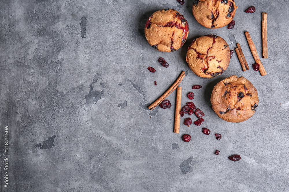Tasty cranberry muffins on grey  table
