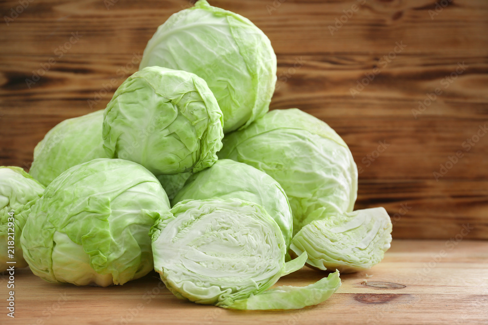 Whole and sliced cabbage on wooden table
