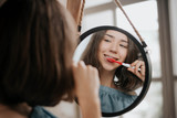 Fototapeta Na ścianę - Beautiful young woman brushing teeth in front of her bathroom mirror.