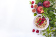 © Marina - Delicious and healthy breakfast on a white background. Porridge of oatmeal, raspberry, honey, bananas, figs, mint fresh for a good morning. Free space for text, top view