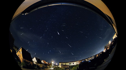 Wall Mural - Perseids Meteorshower Shooting Stars Over A City At Night, a stack of some shooting stars from the perseids meteor shower of 2018 above grossenhain in saxony germany.