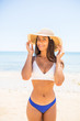 © F8  \ Suport Ukraine - Stylish latin woman in straw hat and sunglasseson the beach on a sunny day
