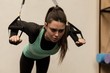 © Wavebreak Media - Young woman exercising with suspension cable in gym