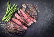 © HLPhoto - Barbecue dry aged wagyu flank steak sliced with green asparagus as top view on an old rusty board with copy space right