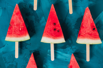 Wall Mural - a view from above on the lobules of watermelon on sticks laid out on a blue background