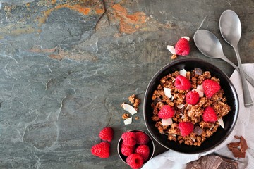 Poster - Healthy breakfast granola topped with dark chocolate, raspberries and coconut. Top view border over a dark background. Copy space.