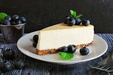 Poster - Slice of cheesecake with blueberries. Close up scene with a dark background.