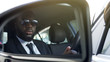 Black man in sunglasses driving car, looking in side-view mirror, bodyguard