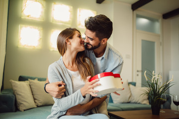 young woman receiving a surprise gift box from her boyfriend at home.