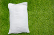 Fertilizer and soil white bag on green grass background