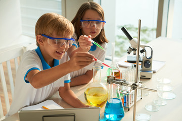 school children adding red and blue liquids into test-tube