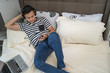 © Kencana Studio - asian man using handphone and listening to music at bedroom