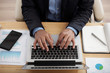 © DragonImages - Hands of man working on laptop at his office table, view from above