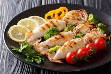 Wall Mural - grilled calamari with tentacles with tomatoes, broccoli, lemon and pepper closeup. horizontal