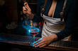 Attractive sexy barmaid spraying blue-colored bitter on the glass