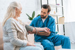 © LIGHTFIELD STUDIOS - young male nurse measuring blood pressure to senior woman