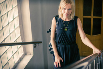 A middle-aged woman in a black dress climbs the stairs inside the building.