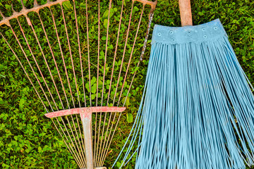 Metal rake and blue plastic broom on top