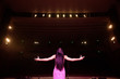 © nagaets - Beautiful singer against the auditorium. Back view girl in long gown performing on stage.