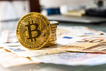 Golden Bitcoin coins on a background of Euro banknotes. 