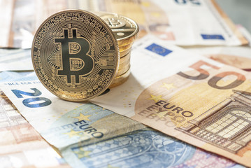 Golden Bitcoin coins on a background of Euro banknotes. 