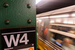New York City subway station with moving train passing by.