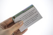Permanent resident or green card in envelope cover with instructions with english and Spanish languages in woman's hand on white background.