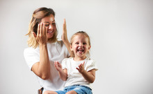 Little Girl Playing Peekaboo Game With Her Mother On White Background With Copy Space. Woman And Child Are Playing Peek-a-boo And Having Fun. Parenthood And Happy Moments Concept