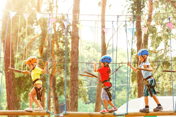 Adventure climbing high wire park - people on course in mountain helmet and safety equipment