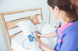 Nurse checking blood pressure of senior female patient who sleeping on bed