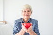 © gamelover - Senior female with white color hair holding heart shape ball and smiling at camera