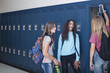 © Brocreative - Candid photo of Three Junior High school Students talking together in a school hallway. Diverse Female school girls smiling and having fun together during a break at school standing by their lockers