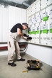 © pavelgulea - Electrician with box of tools testing fuse box or switch box by measuring device