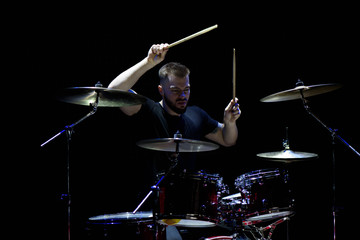 music, people, musical instruments and entertainment concept - male musician with drumsticks playing drums and cymbals at concert or studio