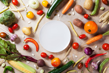 Wall Mural - Autumn farm vegetables, root crops and white plate top view with copy space for menu or recipe. Healthy food on kitchen table.