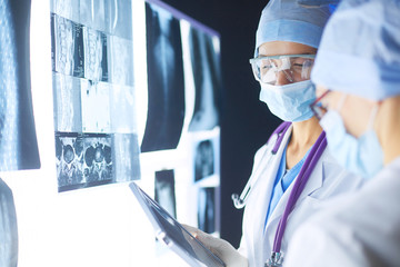 Wall Mural - Two female women medical doctors looking at x-rays in a hospital.