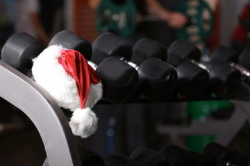 Santa Claus hat on stand with dumbbells in gym