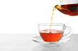 Pouring hot tea into glass cup on white background