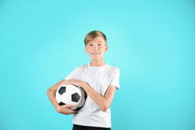 Portrait Of Young Boy Holding Soccer Ball On Color Background