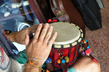 Wall Mural - Hands of man playing African drum or djembe inside a music shop. Chiang Mai, Thailand.