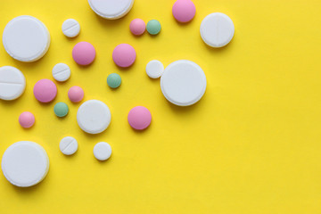 a lot of colorful pills of different shapes on a yellow background. 