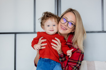 Wall Mural - Mother and toddler baby have a fun at home. Red clothes, autumn season